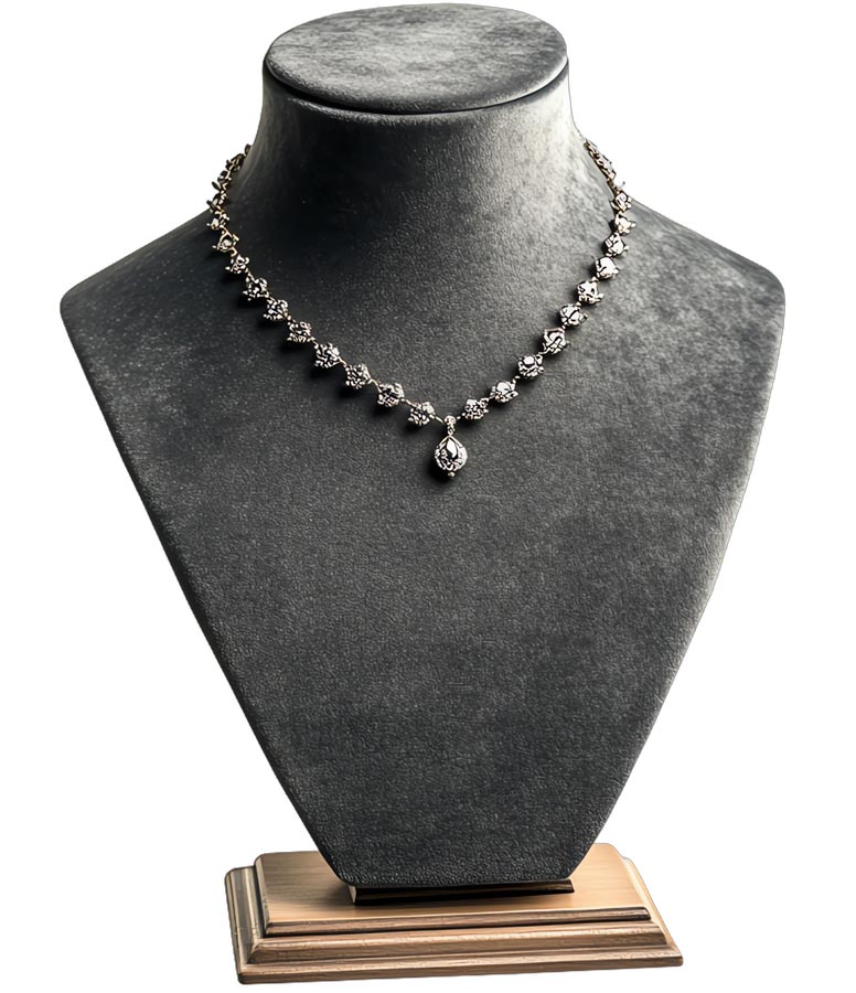 a silver diamond necklace on a gray display bust